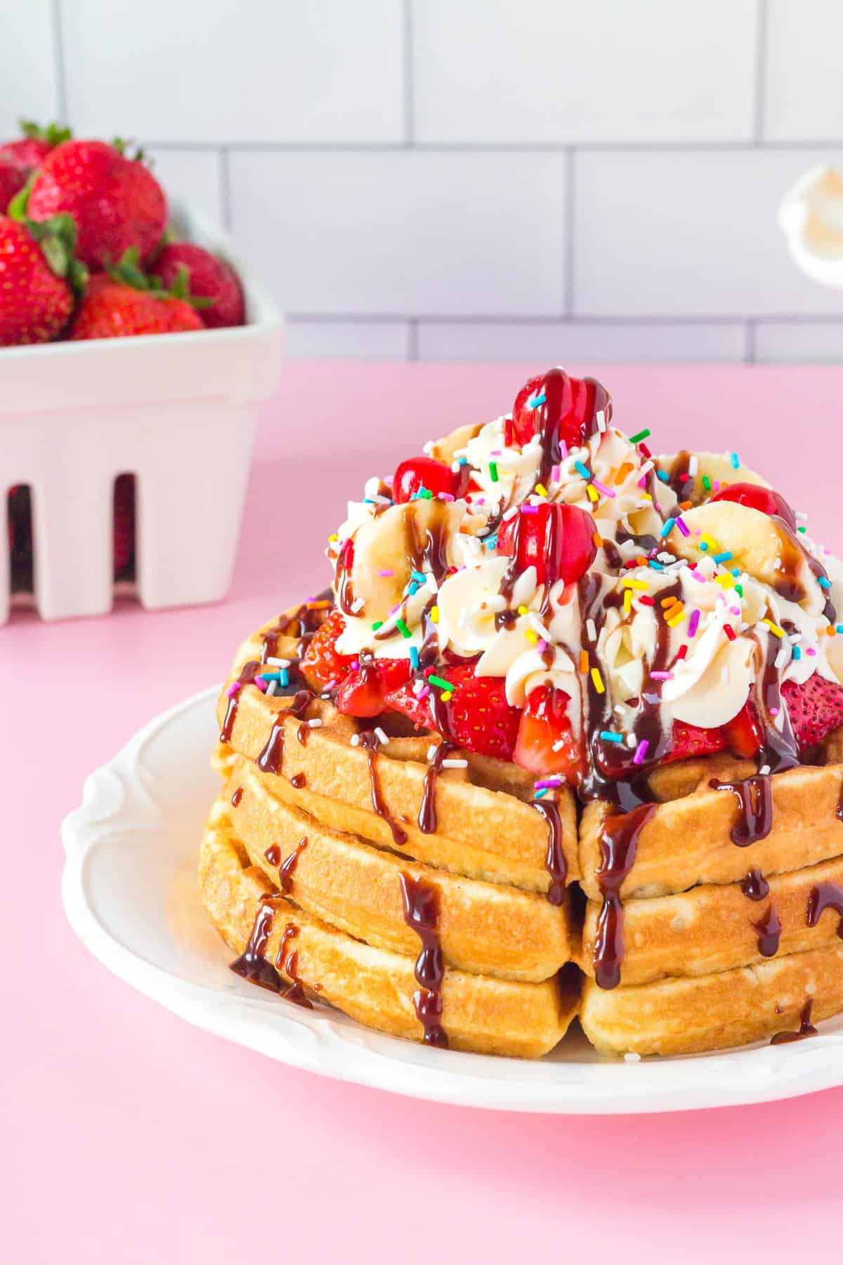 Empilement de gaufres façon banana split avec crème chantilly et garnitures.
