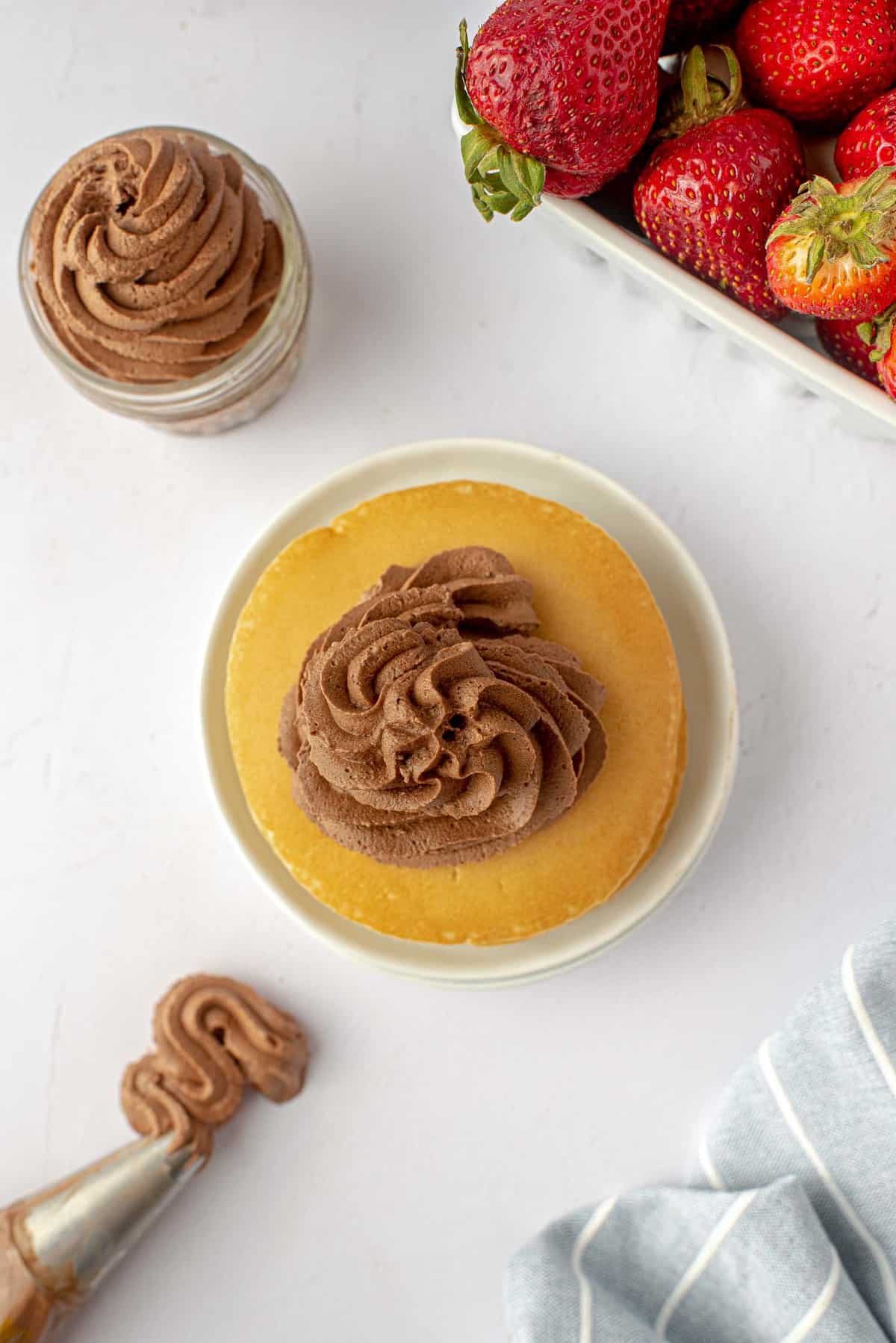 Crème fouettée au chocolat sur des pancakes et dans un petit pot.
