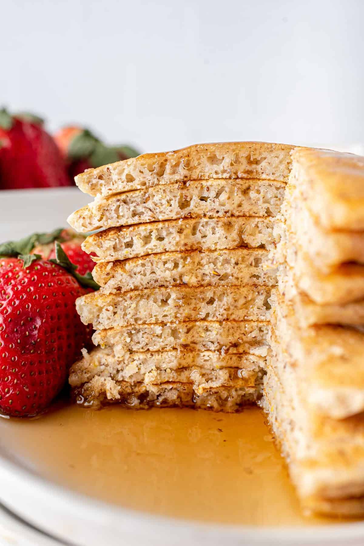 Empilement de pancakes véganes découpés pour montrer la texture, sirop coulant.