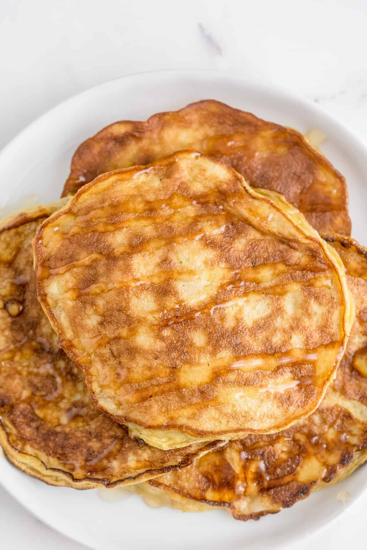 Pile de pancakes à la banane en deux ingrédients sur un plateau blanc.