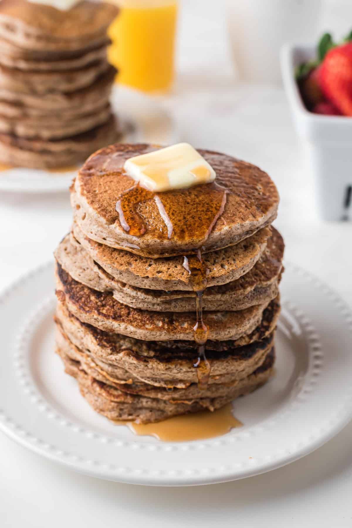 Une haute pile de pancakes avec du beurre et du sirop.
