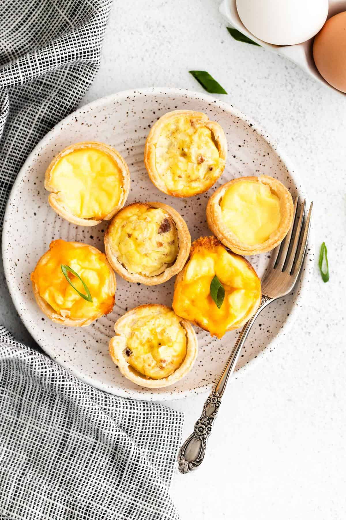 3 variétés de mini quiches sur un petit plateau rond.