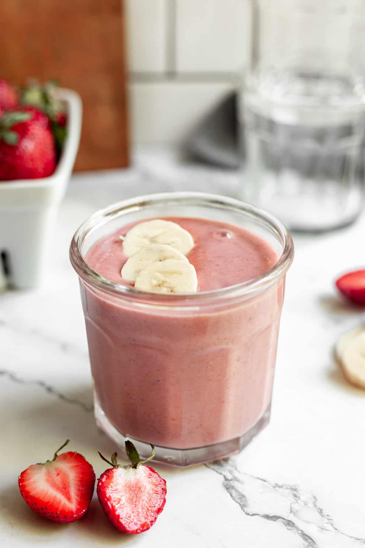 Smoothie fraise-banane-beurre de cacahuète garni de bananes tranchées.