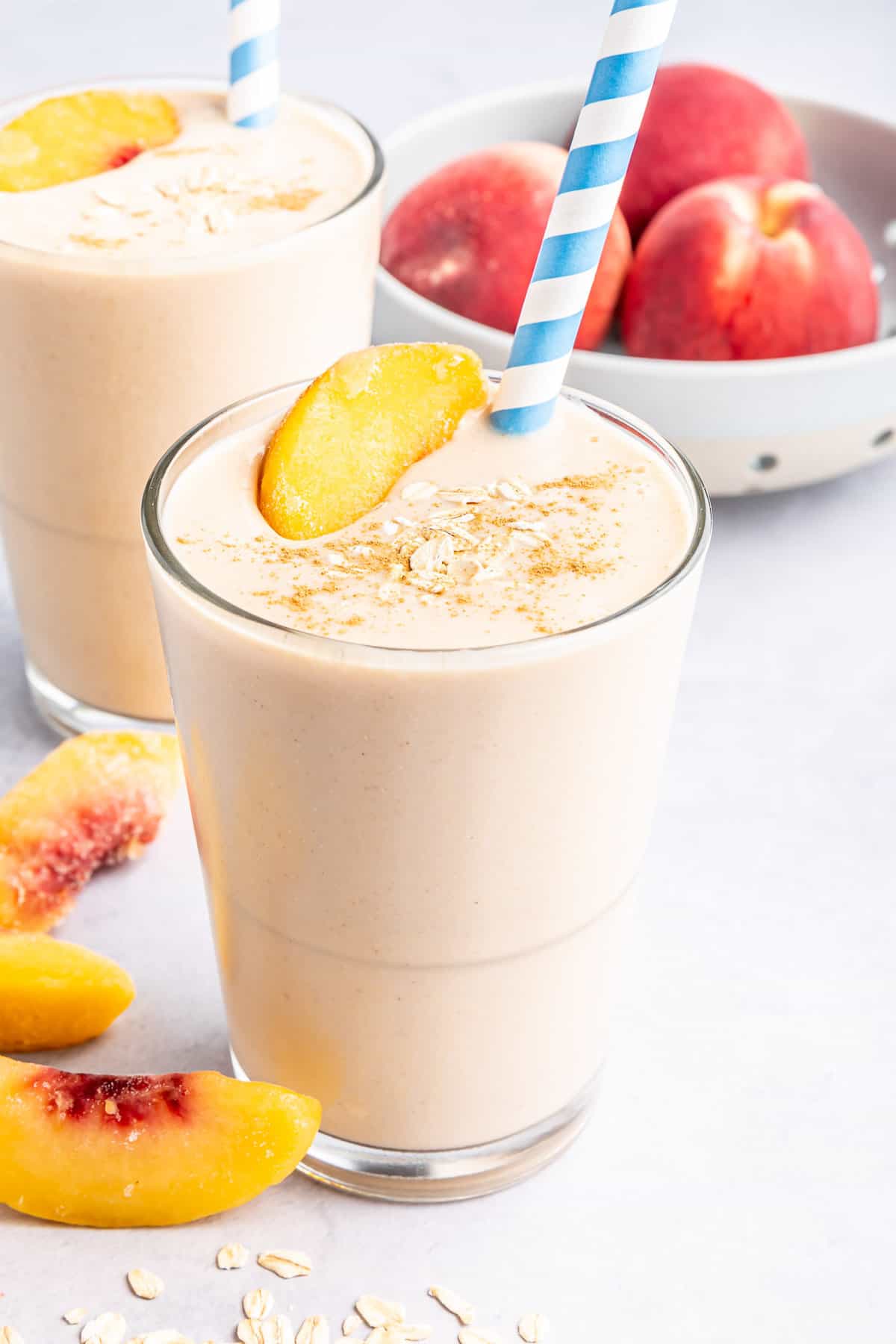 Smoothie aux pêches garni d'une tranche de pêche et d'avoine.